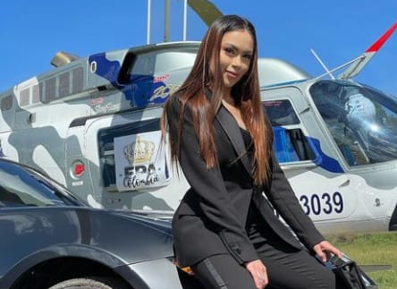 Daneidy Barrera stands in a front of a chopper and a car