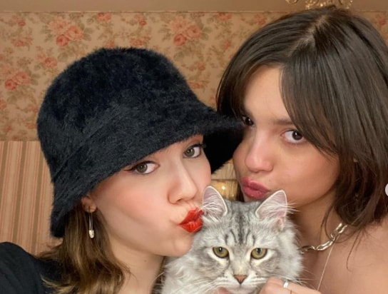 Iris Apatow with her sister Maude Apatow kissing a cat
