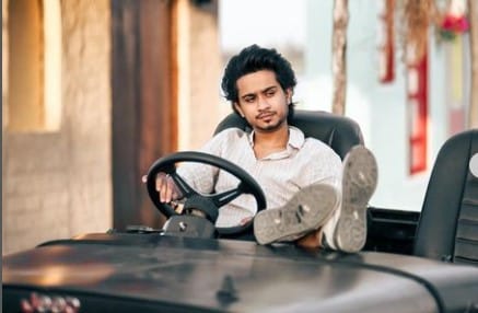 Ansh Pandit sitting on his luxurious car