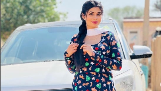  Ruba Khan stands in front of a car