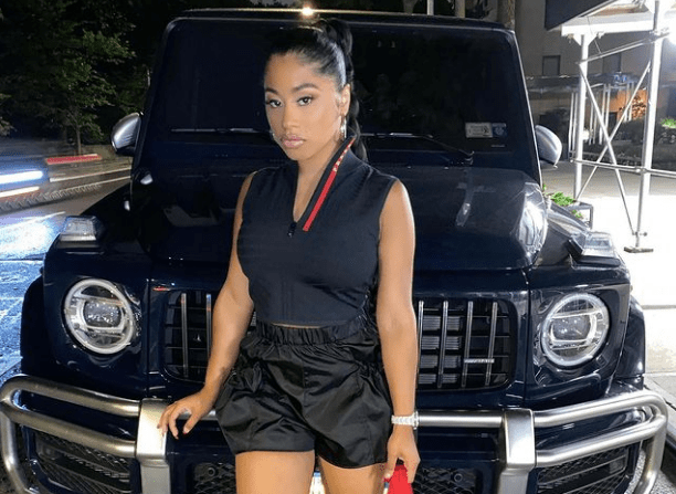 Hennessy Carolina taking pictures in front of her luxurious car
