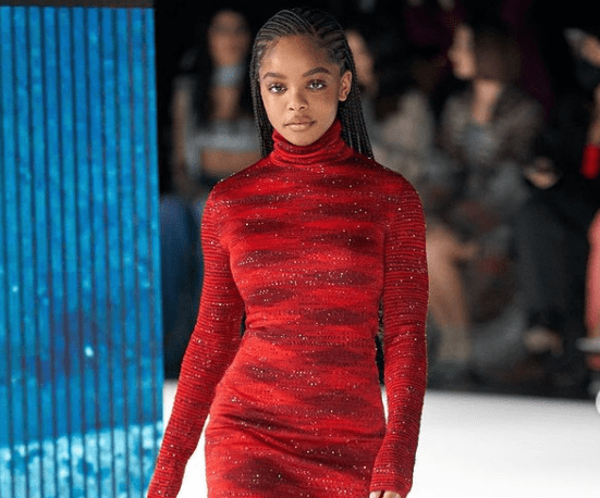 Marsai Martin walks on a ramp in a red outfit